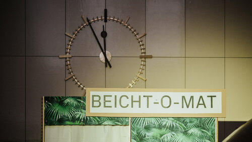 Großer Holzkasten zum Begehen, darauf als Schrift "Beicht-O-Mat"